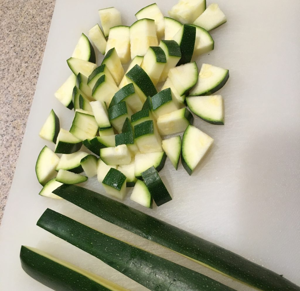chopped zucchini on a white cutting board.