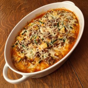 A oval white baking dish with zucchini beef marinara.