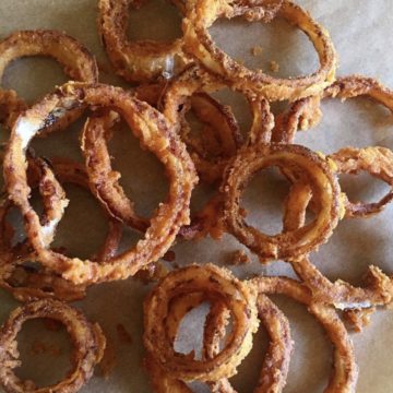 A lot of crispy onion rings piled on top of each other.