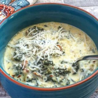 A blue bow filled with keto zuppa toscana soup. A floral cloth napkin to the left of the bowl.