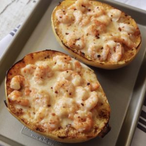 Creamy shrimp Alfredo spaghetti squash on a metal sheet pan. The pan is sitting on a gray and white striped hand towel.