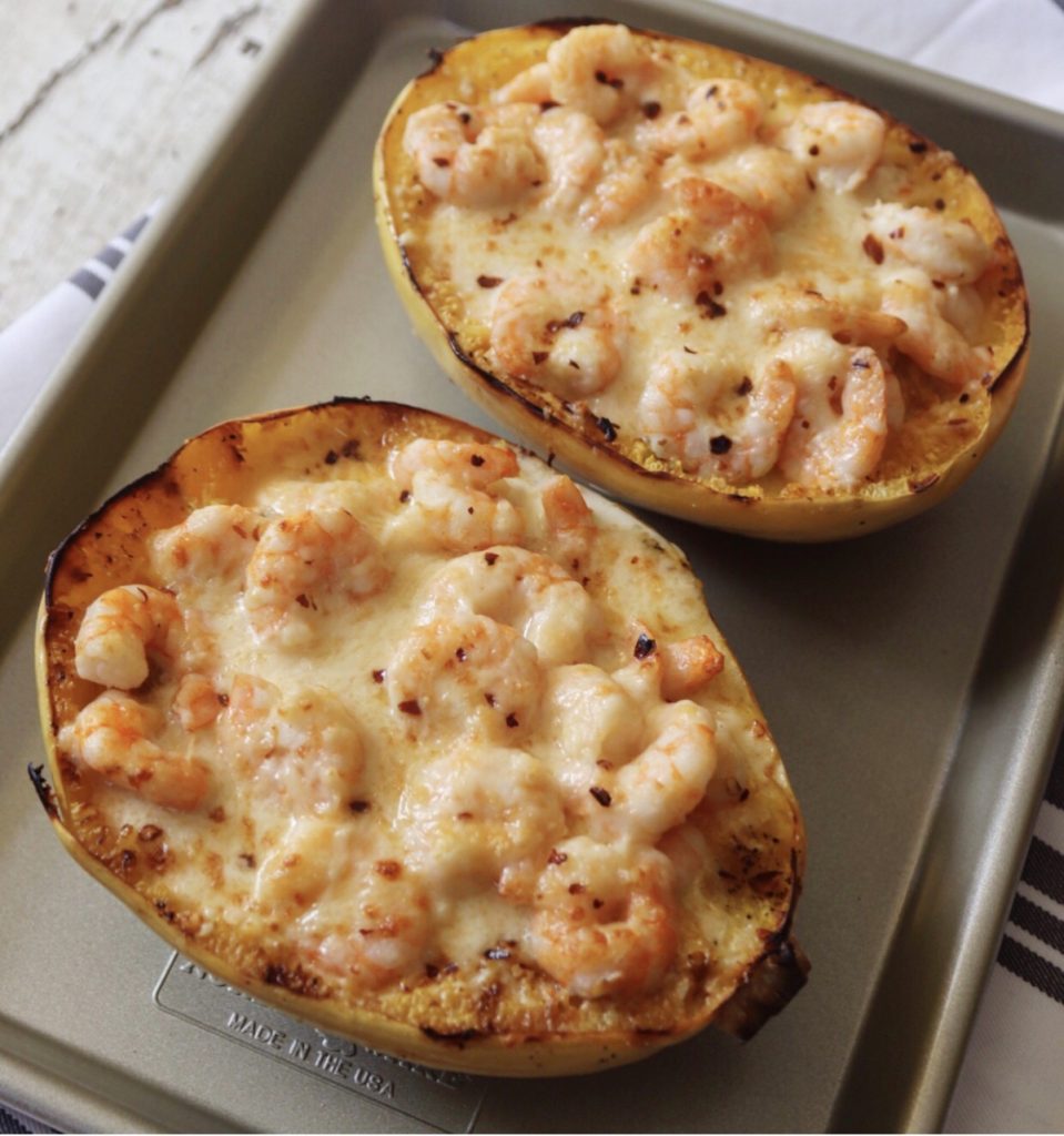 Creamy shrimp Alfredo spaghetti squash on a metal sheet pan. The pan is sitting on a gray and white striped hand towel.