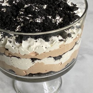 A glass trifle bowl with oreo dirt cake in it.