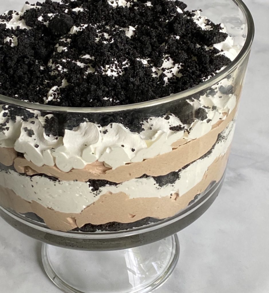 A glass trifle bowl with oreo dirt cake in it.