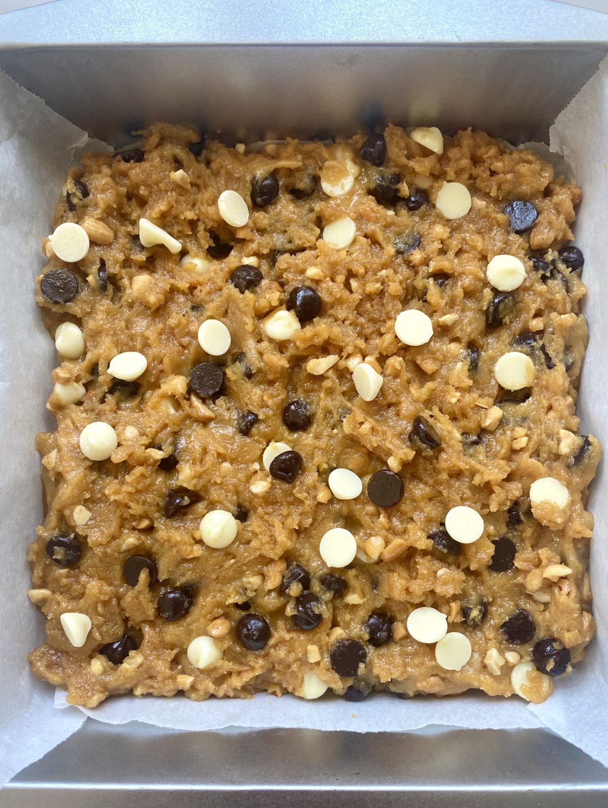 Unbaked peanut butter chocolate chip bars in a metal pan.