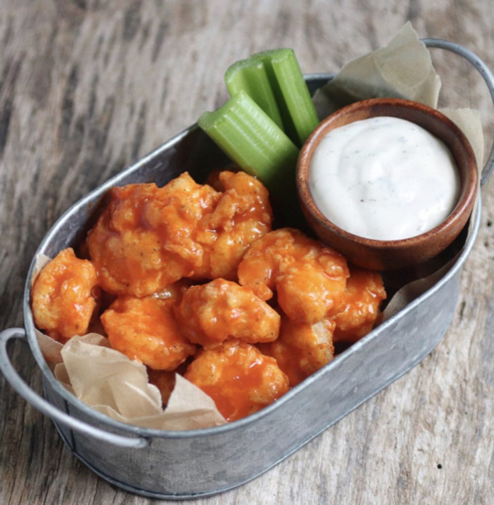 Buffalo shrimp, celery and ranch dressing in a metal basket.