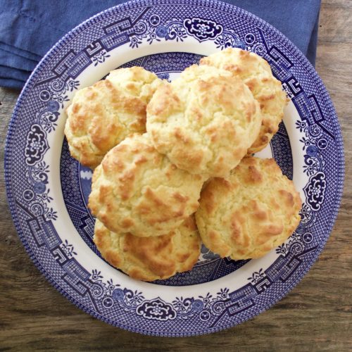 drop biscuits on a blue and white plate beside a blue napkin.