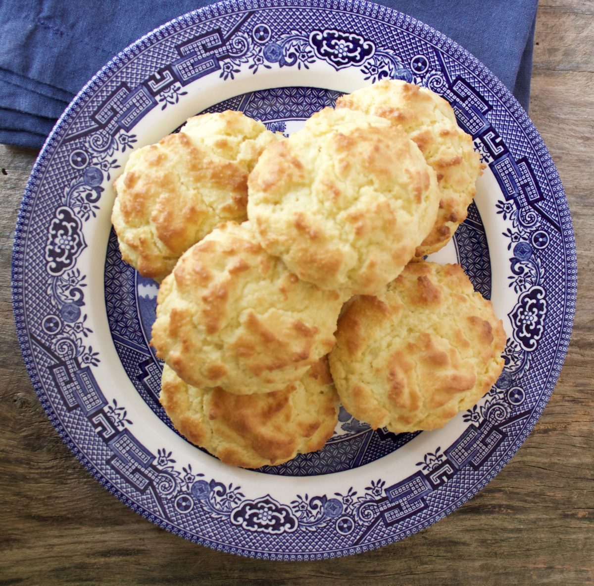 drop biscuits on a blue and white plate beside a blue napkin.