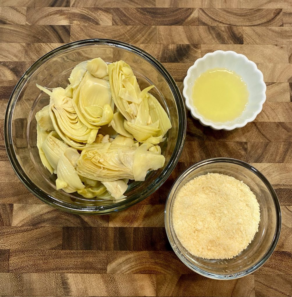 ingredients in clear bowls, artichokes, avocado oil and parmesan cheese.