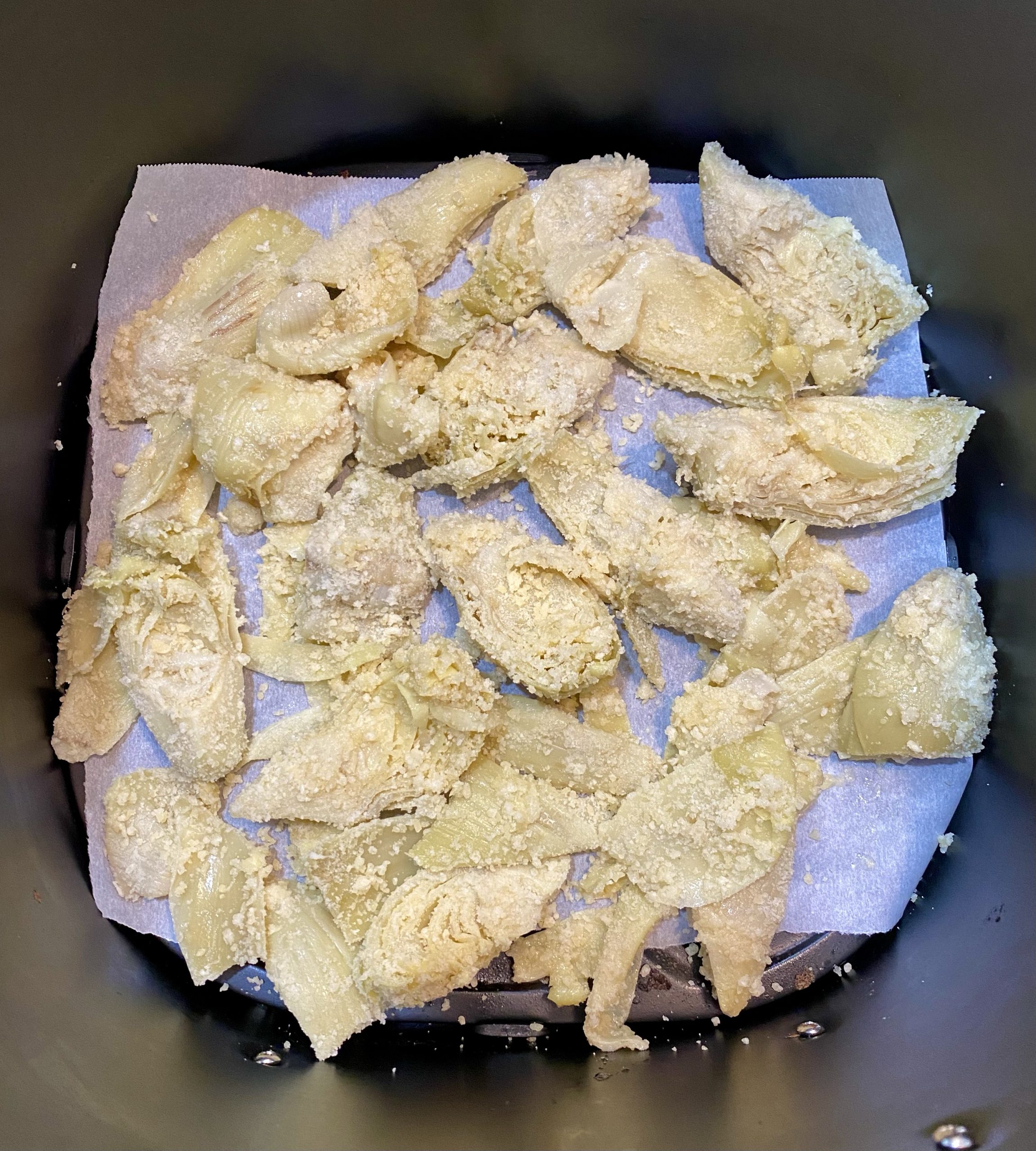 breaded artichokes in air fryer basket.