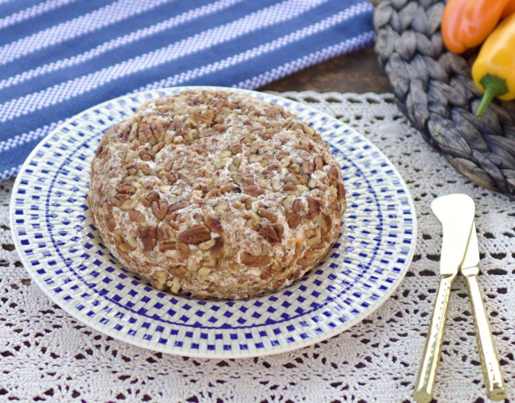 low carb cheddar ranch cheeseball on a blue and white plate. two gold cheese knives.