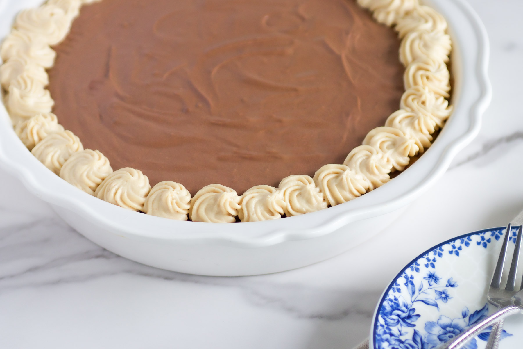 peanut butter chocolate pie in a white ceramic pie plate.  two forks a ble and white plate.