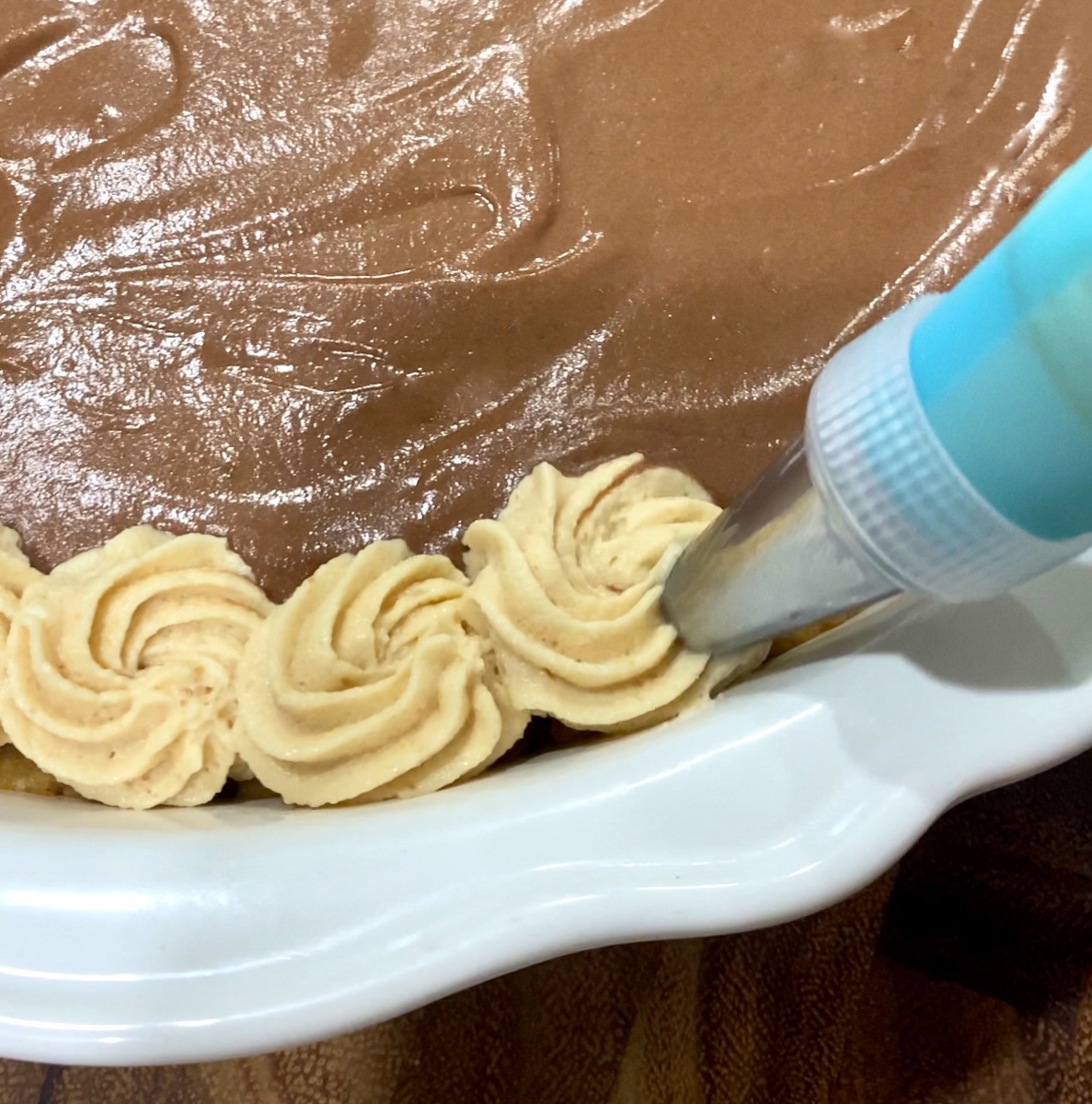 a piping bag piping peanut butter pie filling on to the pie.