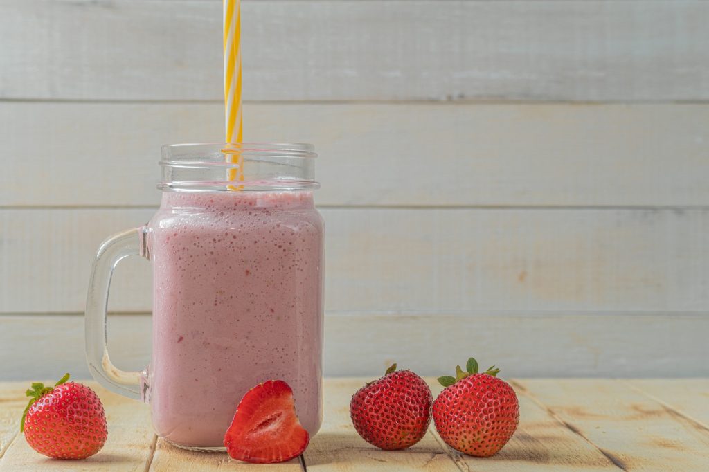 Low Carb Berry Smoothie in a clear jar with a yellow straw.