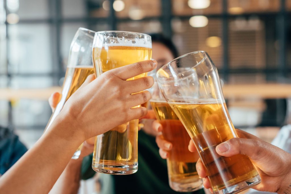 Several hands holding beer glasses, toasting.