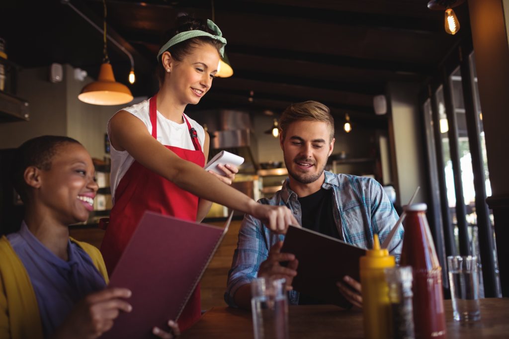 waitress talking to a man and woman.