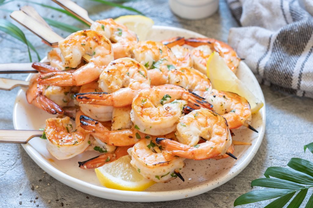 Cooked Shrimp on Skewers and lemon slices.