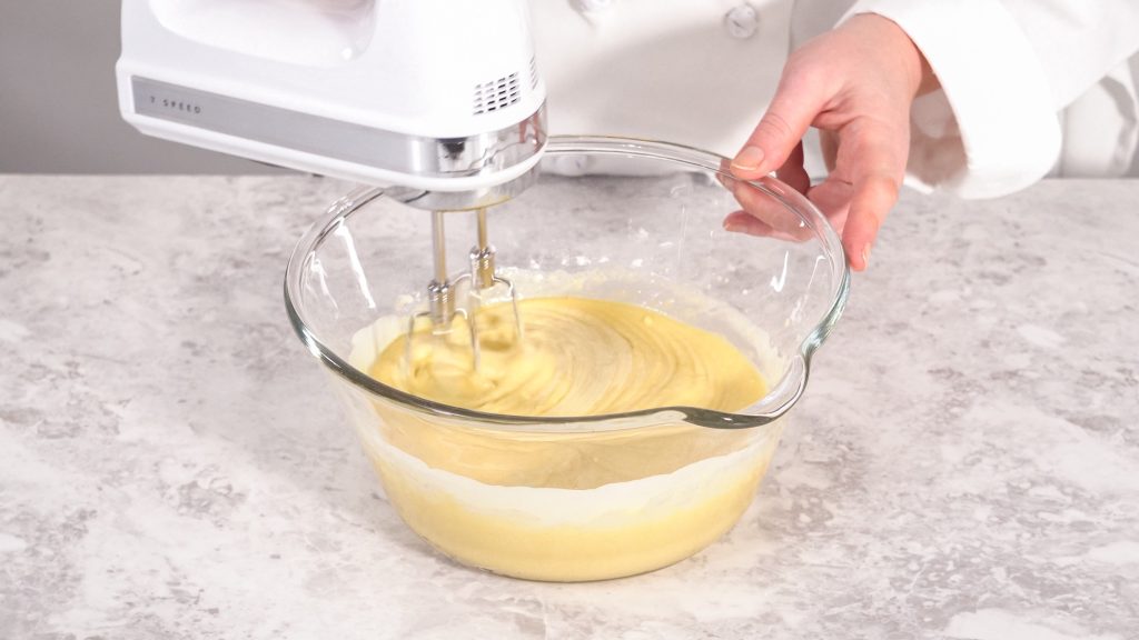 Clear bowl, hand using a stand mixer to mix ingredients.