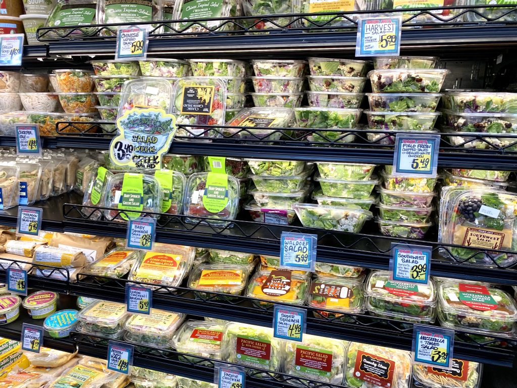 Premade salads in grocery store cold case.