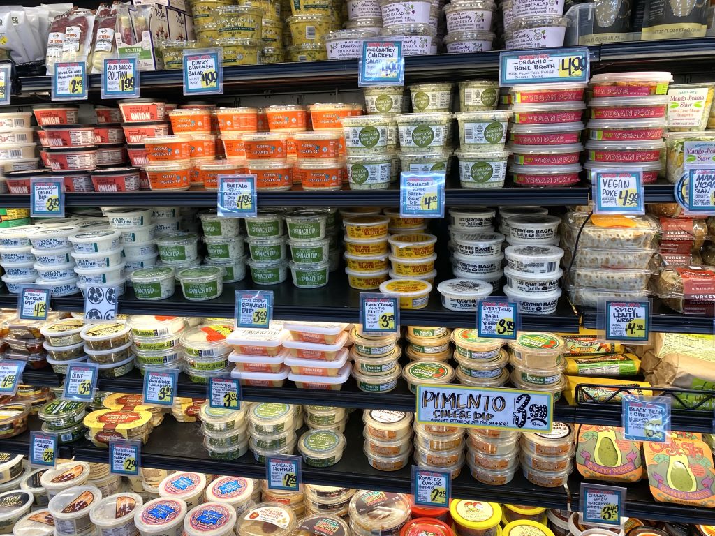 Variety of dips in the grocery store cold case.