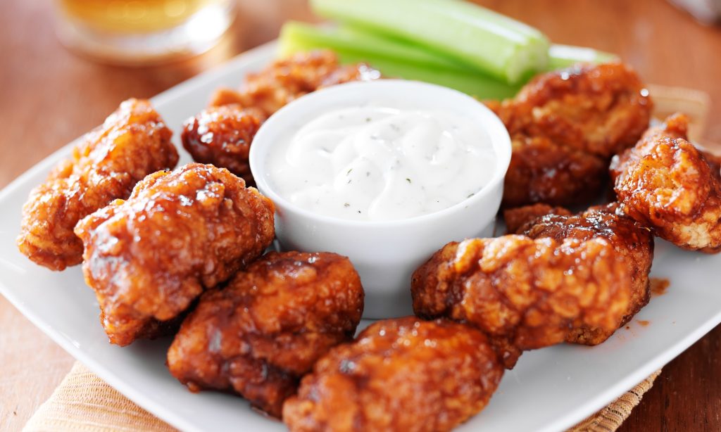 a plate of buffalo wings with a bowl of ranch dressing in the middle.