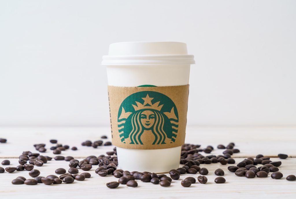 A starbucks cup surrounded by coffee beans.