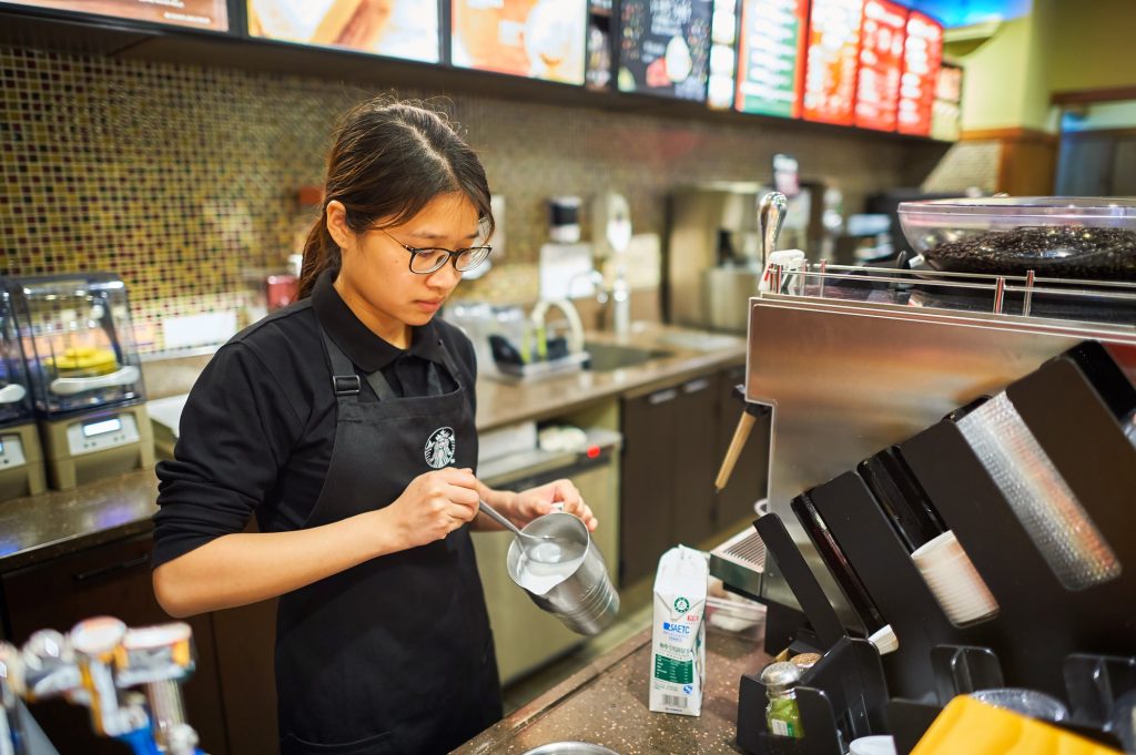 a starbucks barista frothing milk.