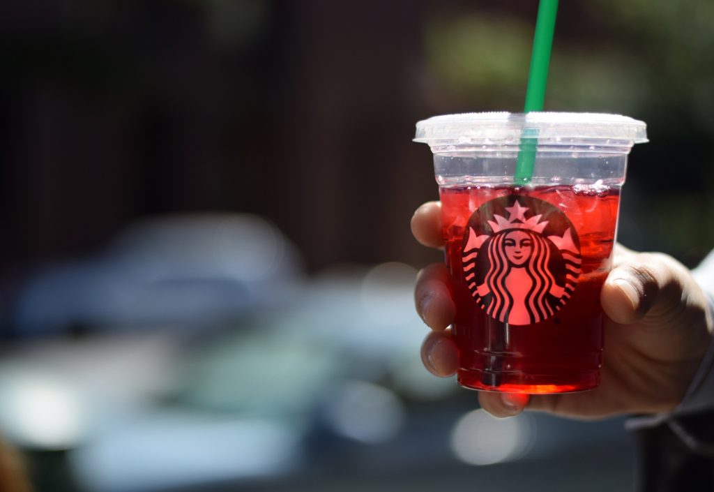 Hand holding starbucks iced pink drink.