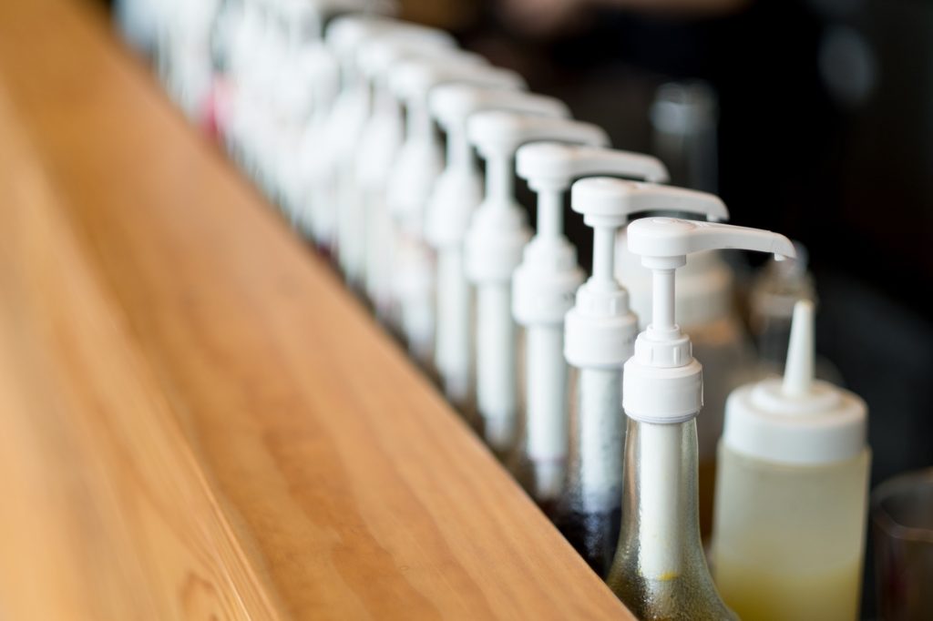 Coffee syrup bottles lined up. 