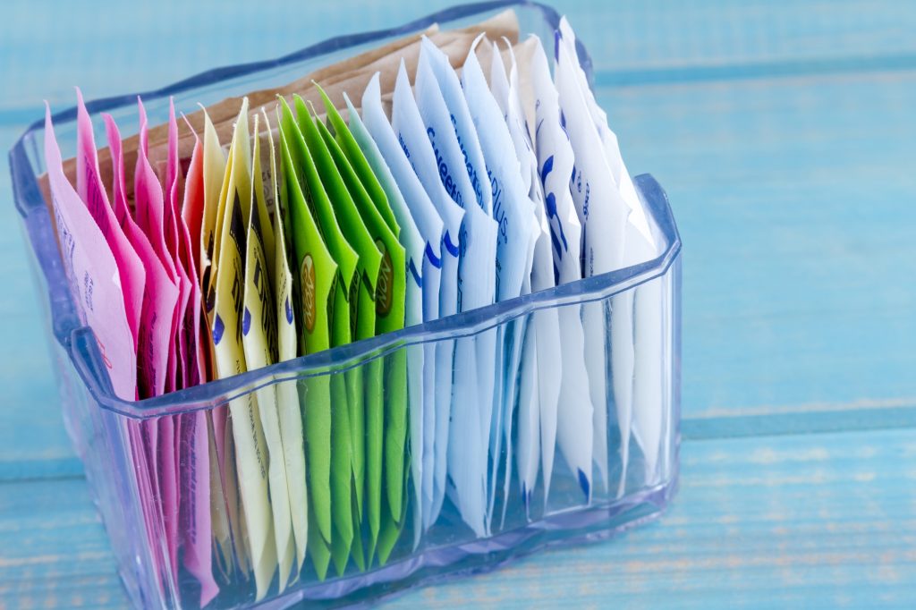 A plastic container with packets of sweetener in it.