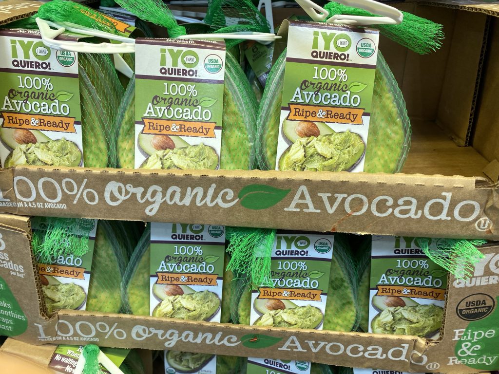 Precut avocado on grocery shelf.