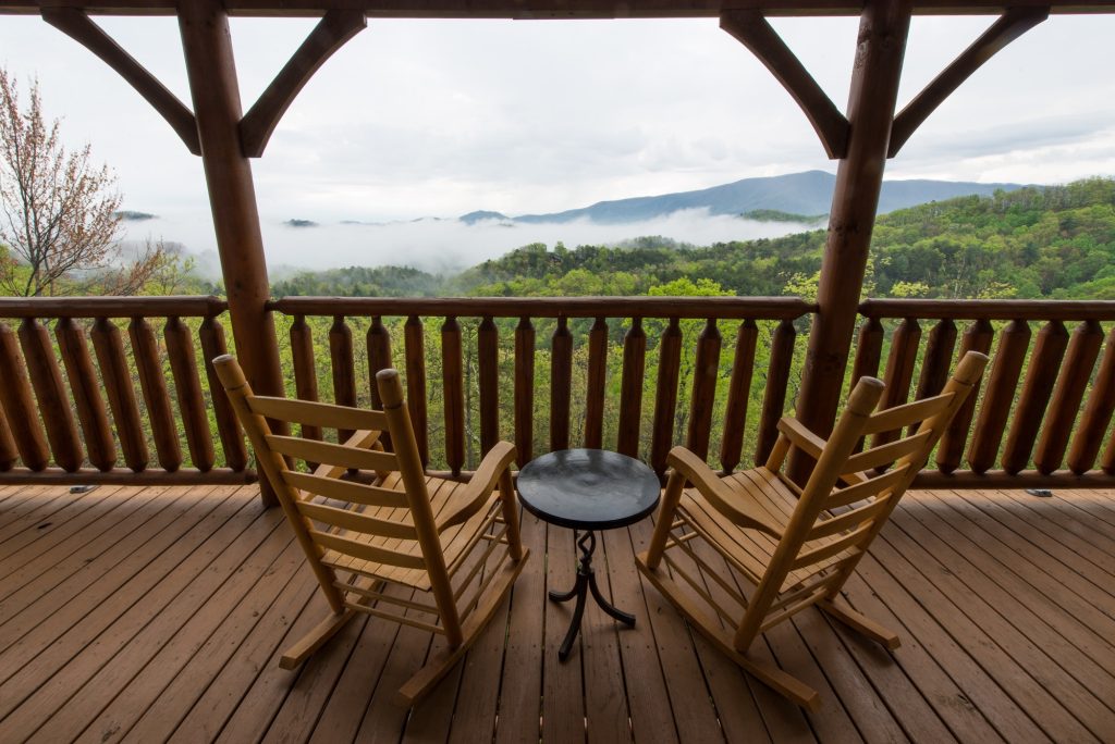 Two rocking chairs on a cabin deck overlooking the smoky mountains.
