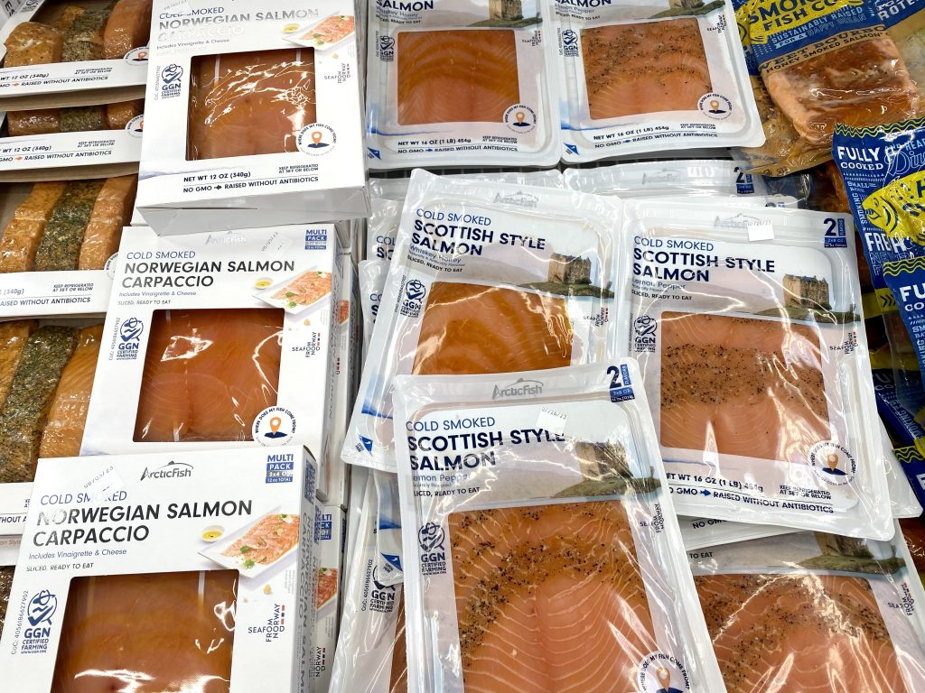 Packages of smoked salmon in a refrigerated cooler at grocery.