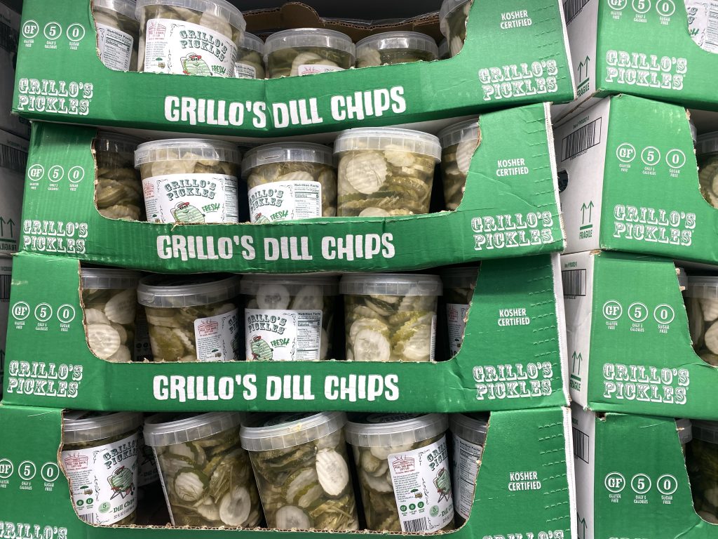 Stacks of containers of pickles on grocery shelf.