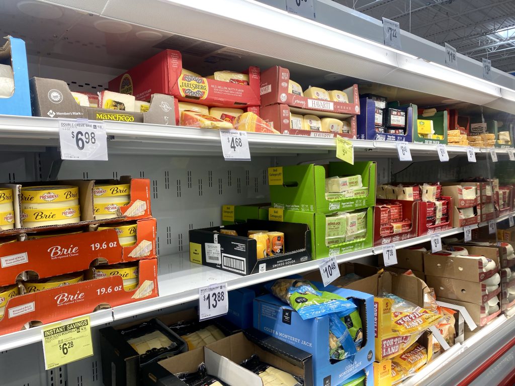 Refrigerated isle of cheeses at grocery.