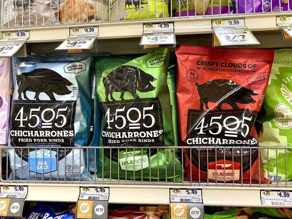 packages of pork rinds on grocery shelf. 