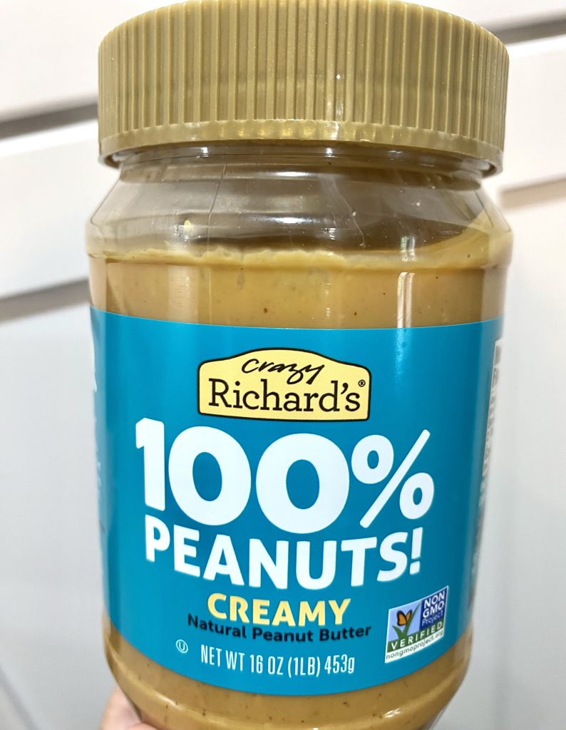 A jar of crazy richards 100% peanuts creamy peanut butter.