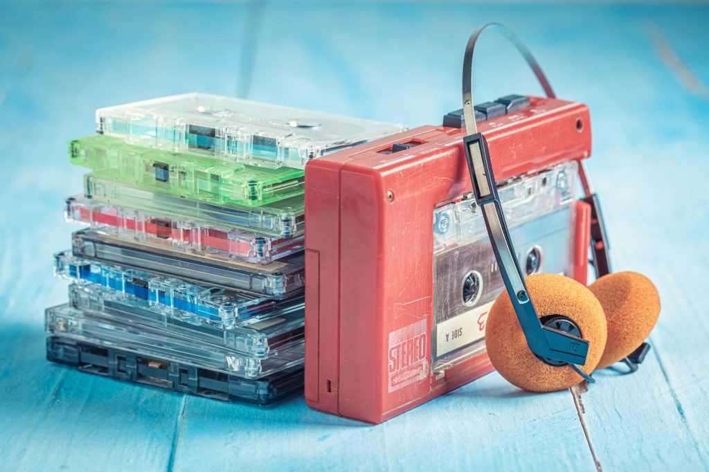 Vintage walkman and earphones and several colorful casette tapes.