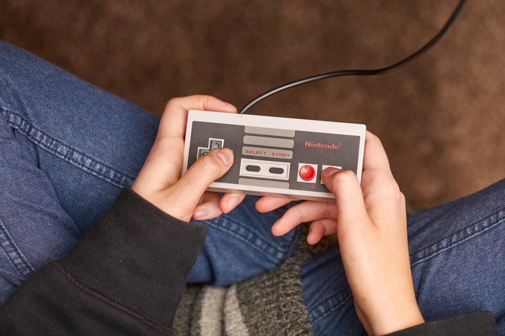 Hands holding a vintage gaming Nintendo player.