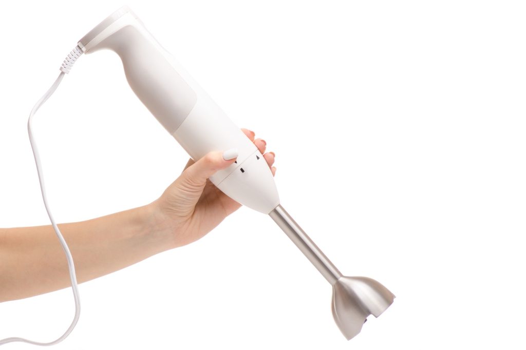 Hand holding a white immersion blender.