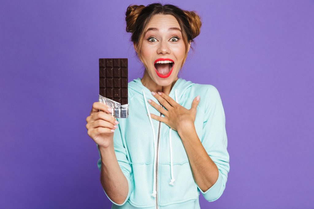 Excited woman holding a chocolate candy bar.