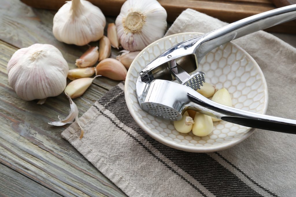 Garlic press and several bulbs of garlic.