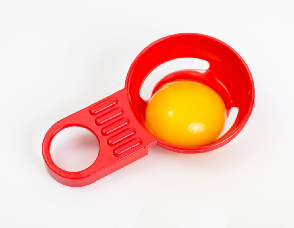 red egg separator with an egg yolk in it.