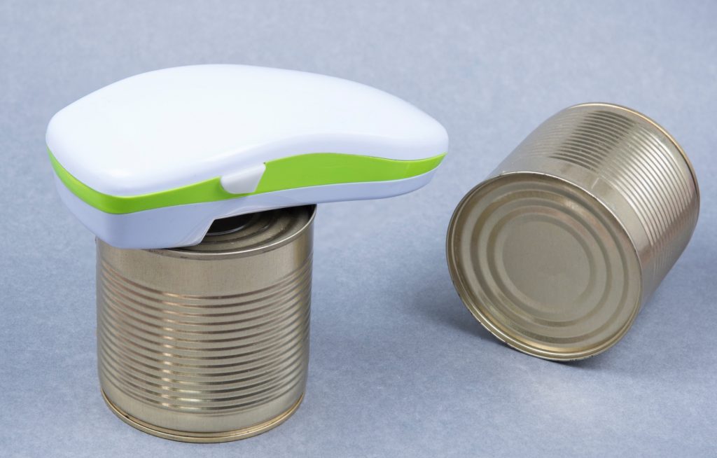 Two cans of food. An electric can opener on top of one of the cans.