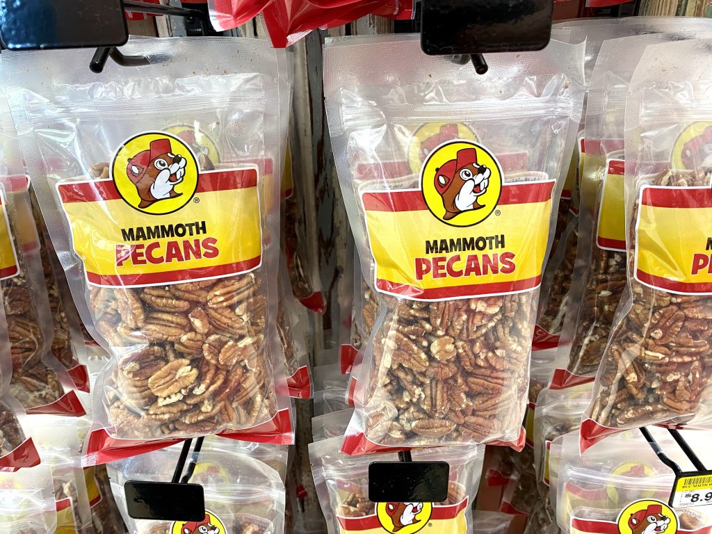plastic bags of Buc-ee's pecans hanging from store shelf.
