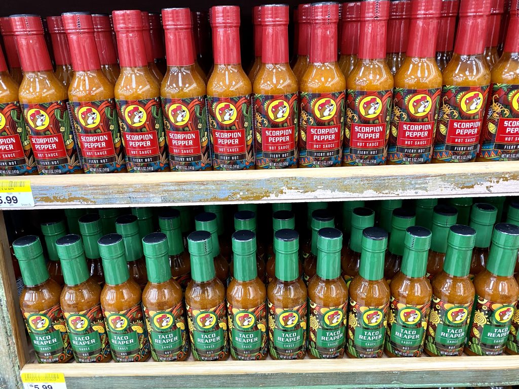 Several flavors bottles of hot sauce on a store shelf.
