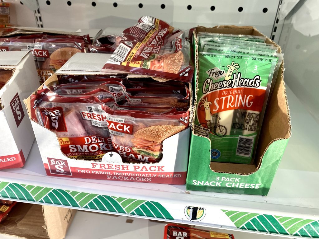 Packages of lunchmeat and cheese in cooler at store.