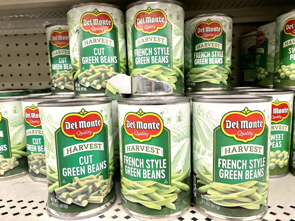 Several cans of green beans on a store shelf.