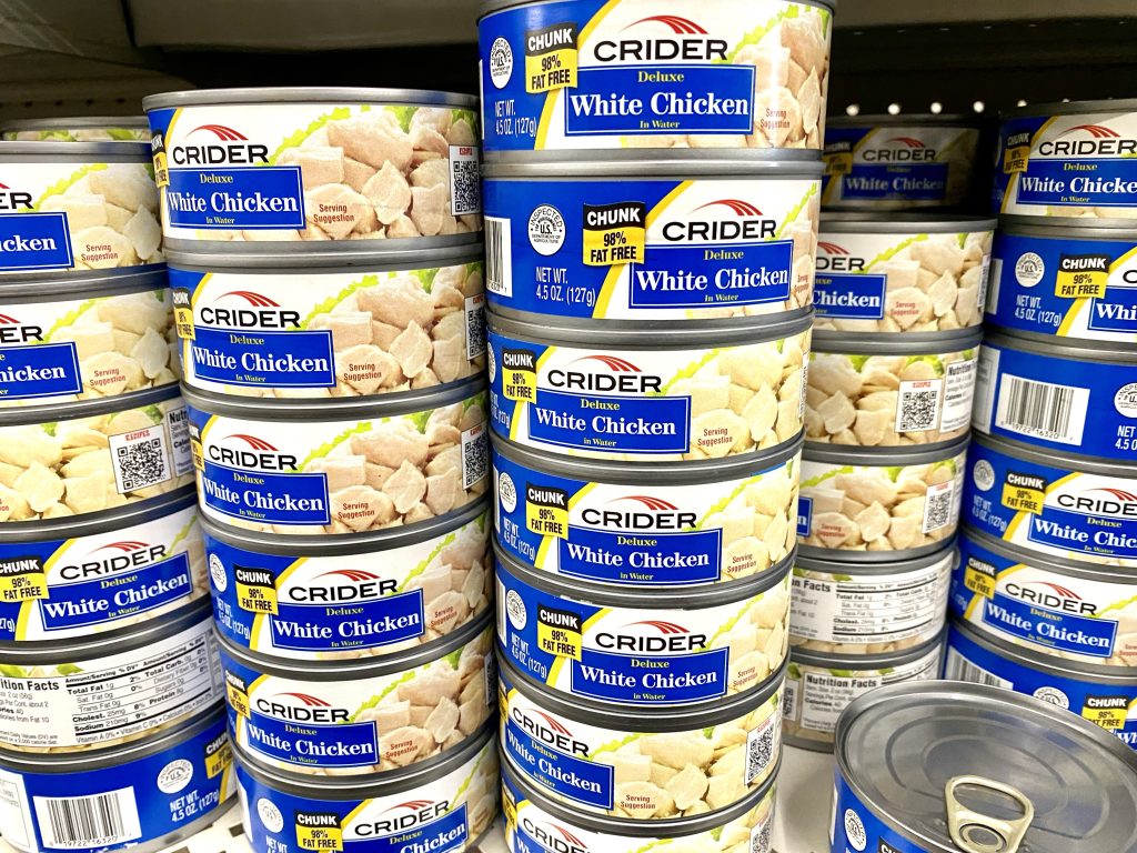 Cans of chicken on a store shelf.