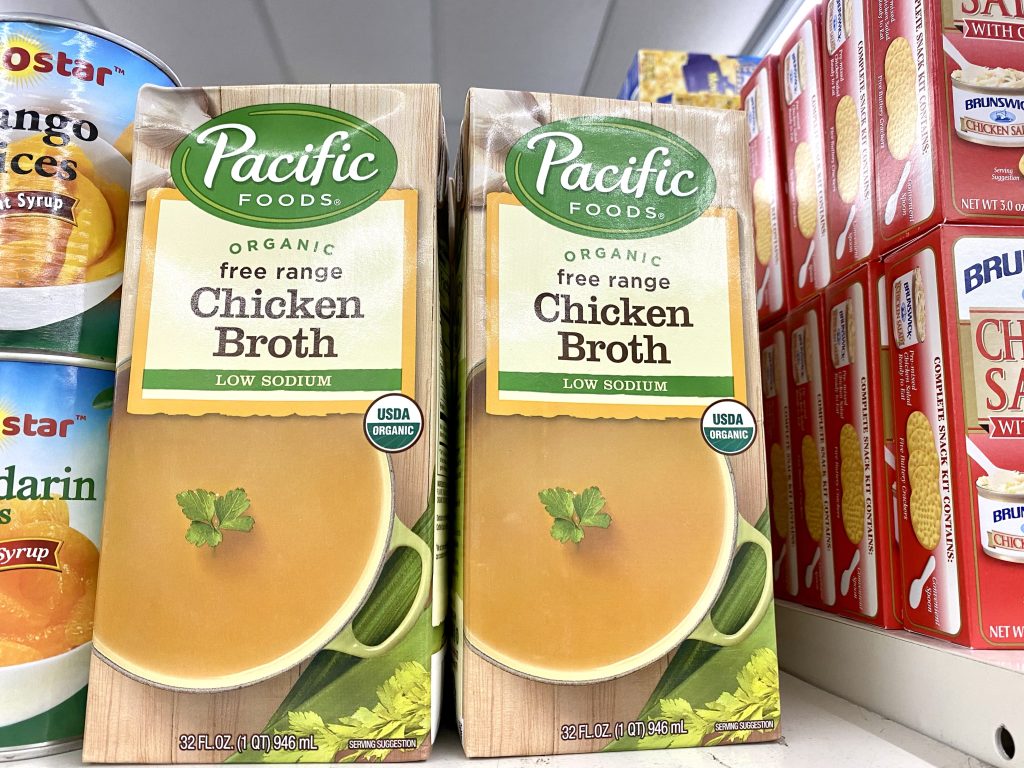 Boxes of organic chicken broth on a store shelf.